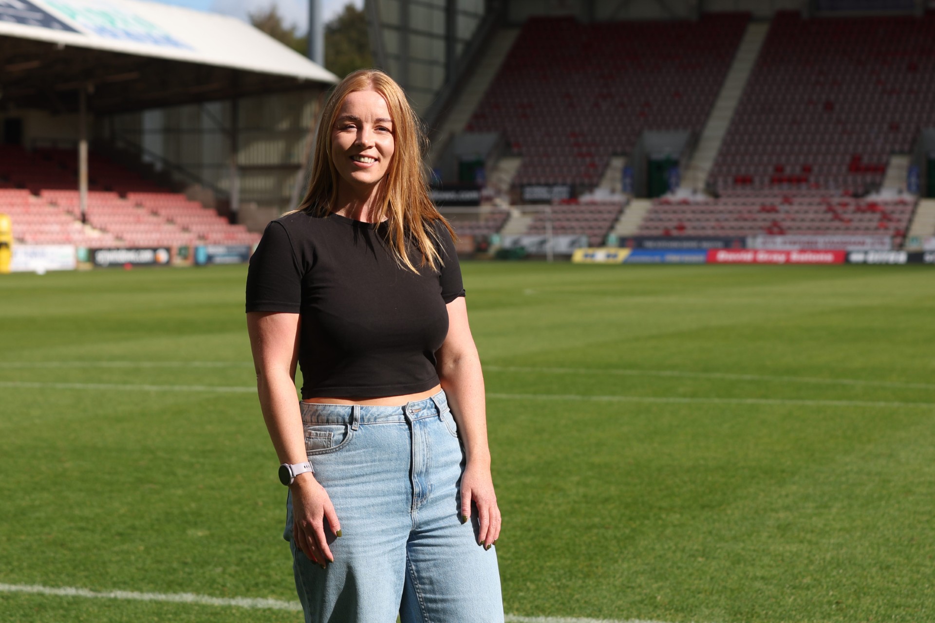 Lindsay Gilfillan Smiling in black top and jeans in the stadium