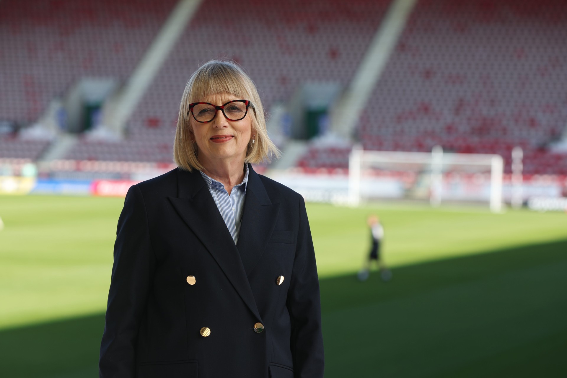 Fiona in the stadium smiling infront of training on the pitch